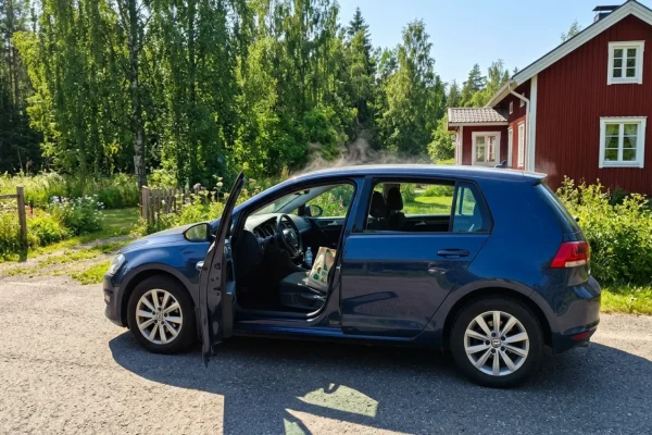 Mies tuulettaa kuumaa henkilöautoa pumppaamalla ovea avoimella parkkipaikalla.