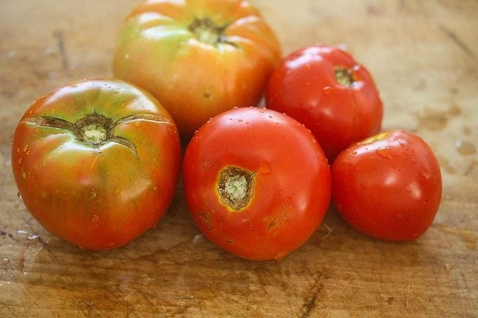 Five Heirloom Tomatoes on wooden chopping board