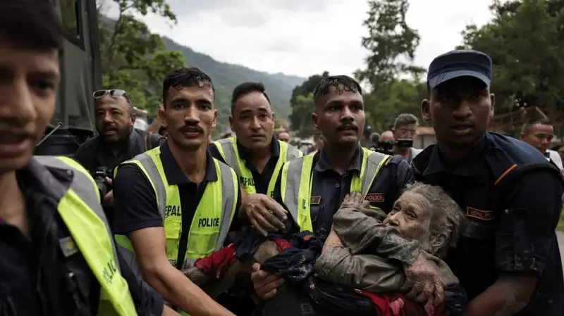 Pelastajat kantavat mutaan peittynyttä naista Nepalin tulva-alueella