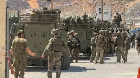 Siirtolaisia ja viranomaisia Ceutan raja-alueella.