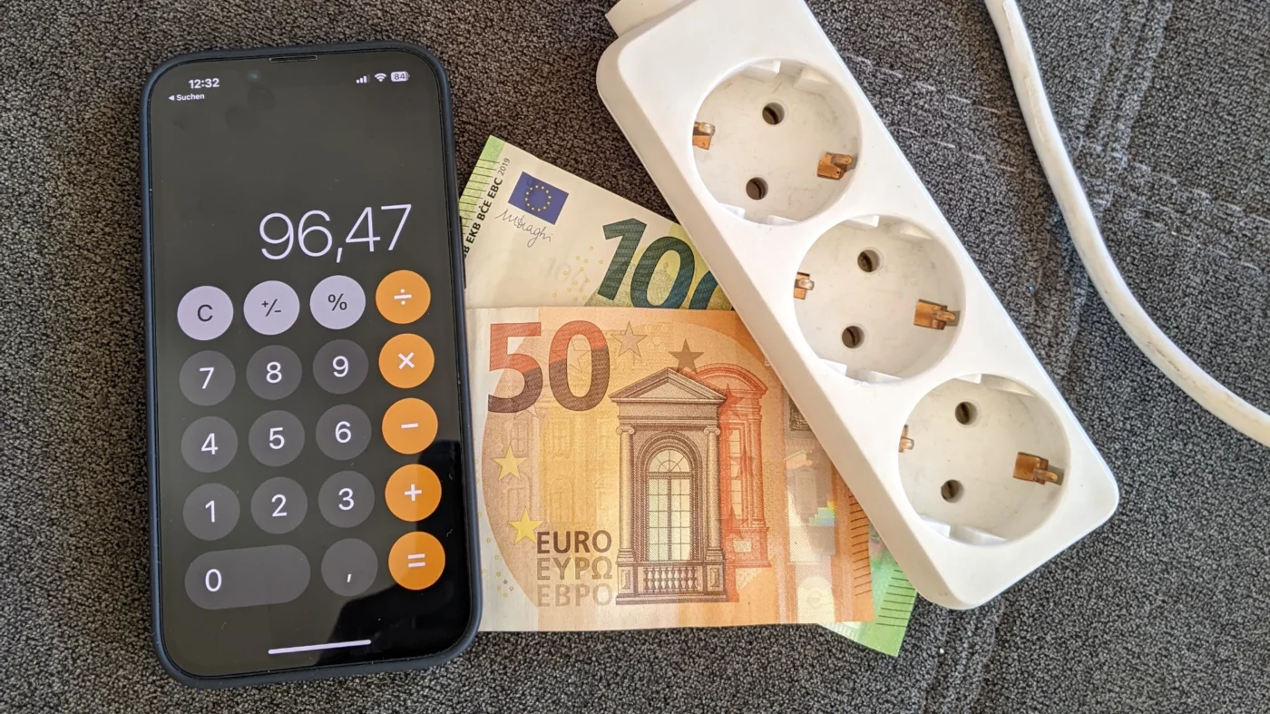Steckdose, Taschenrechner-App und Geldscheine