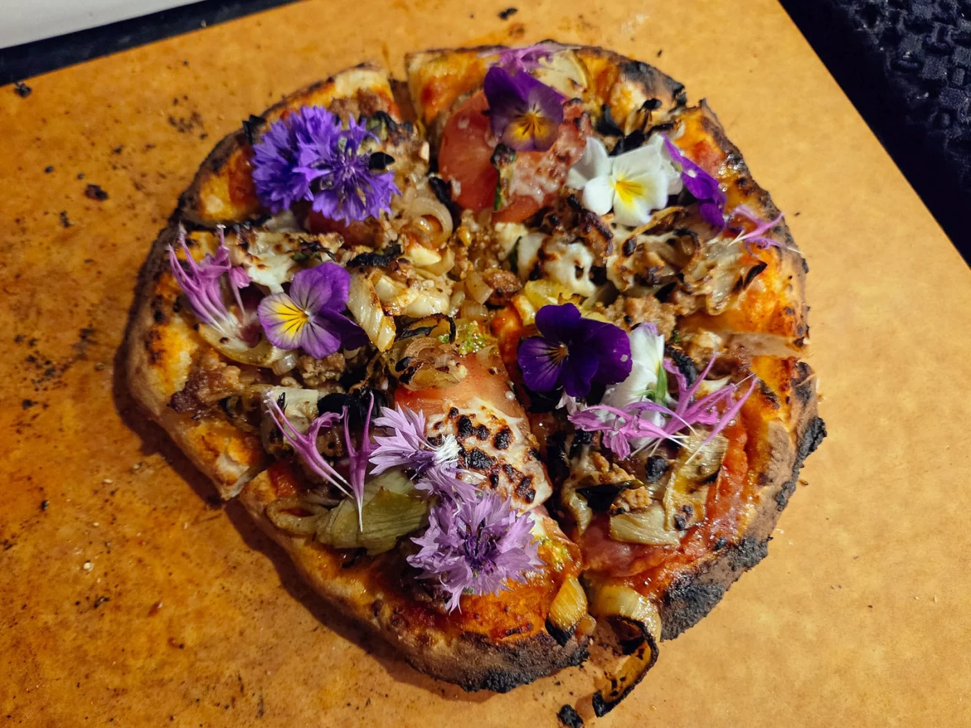 Wood-fired pizza topped with edible violets, bachelor buttons, and bee balm petals